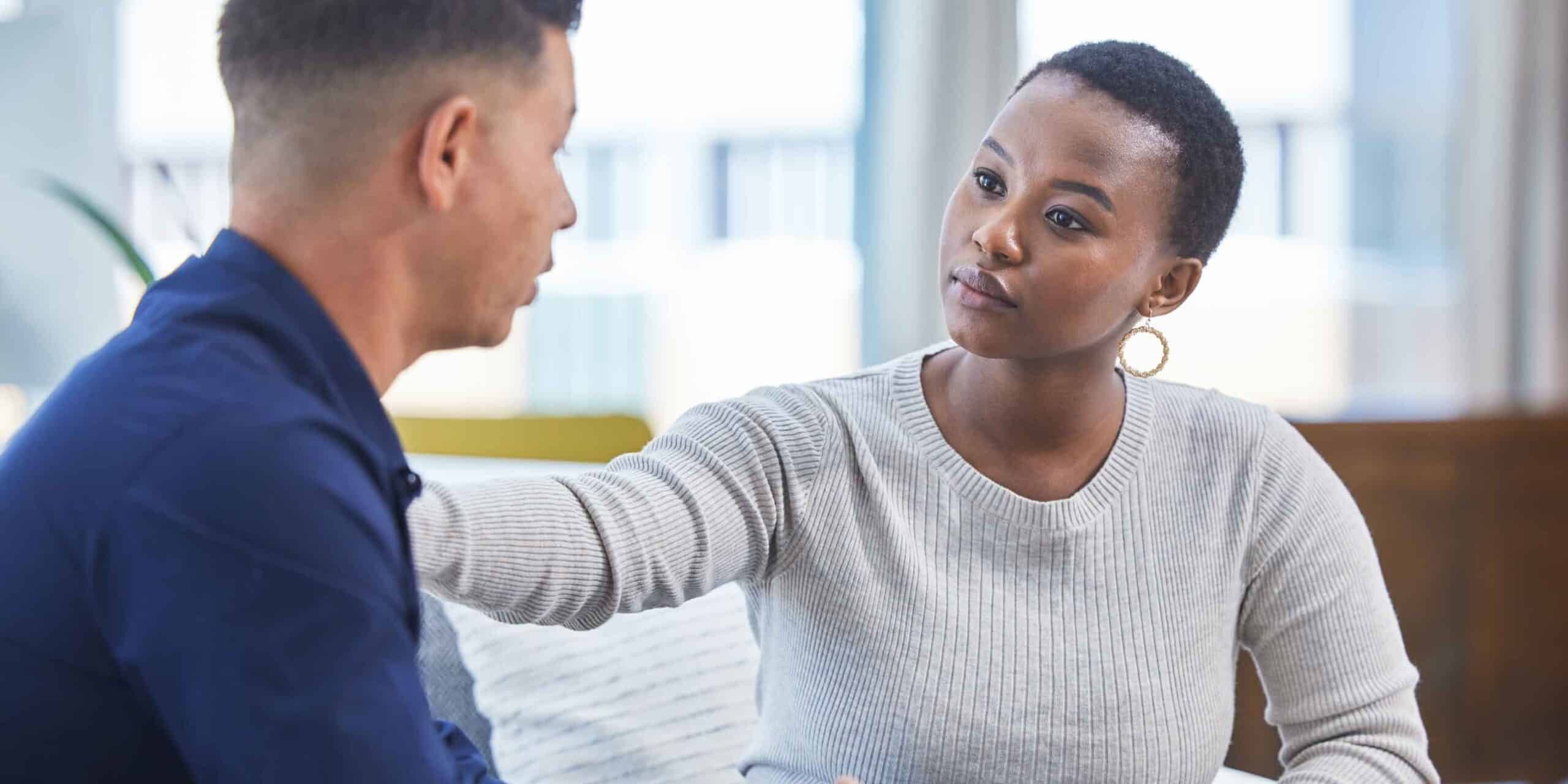 two people sitting down, woman with arm on man's shoulder