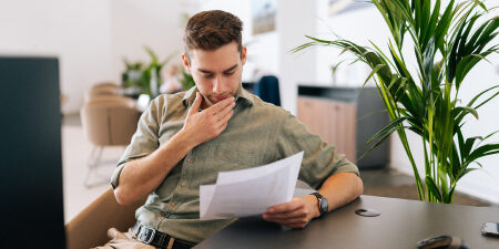 man reading document and scratching his chin