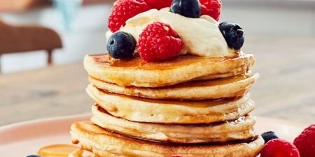 stack of pancakes topped with blueberries and raspberries