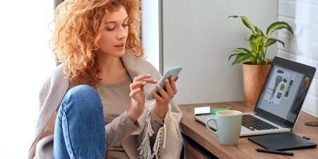 A woman sat at her desk looking on her phone.
