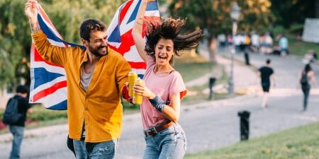 An image of a man and a woman waving a Union Jack flag in a festival park