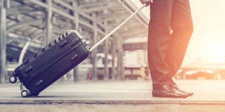 An image of a man pulling a suitcase towards the airport.