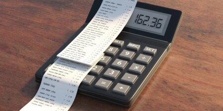 Image of a calculator on a wooden desk with a receipt on top