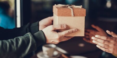 An image of someone passing a wooden gift box to their friend.