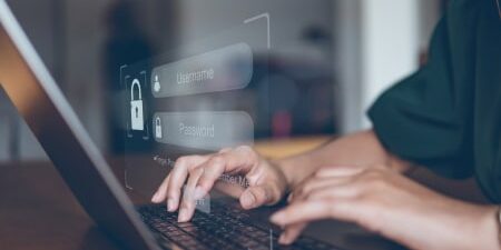 Image of someone typing on their laptop with the screen requesting their username and password.