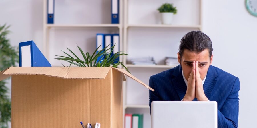 An image of a man sat at his desk with his head in his hands.