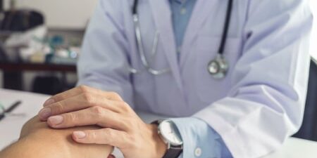 How-To-Deal-With-Debt-When-Terminally-Ill-feature Image of a doctor holding a patients hand.