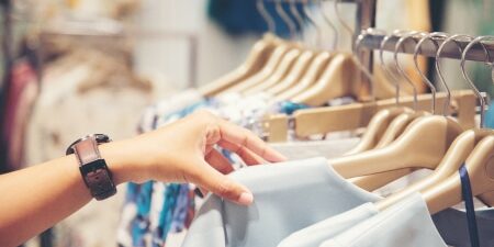 Image of someone searching through a clothes rack in a shop