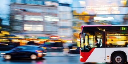 Image of a bus and a car travelling down a main road