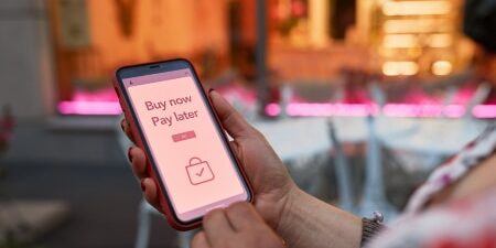 Image of someone looking at their mobile with the words 'Buy Now Pay Later' displayed