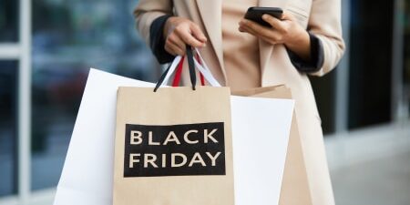 Image of a woman holding a few Black Friday shopping bags.