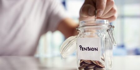 Image of a mason jar with the label "pension" on it with some coins inside.