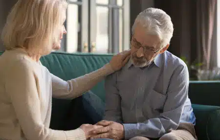 Image of a woman comforting her husband on the sofa