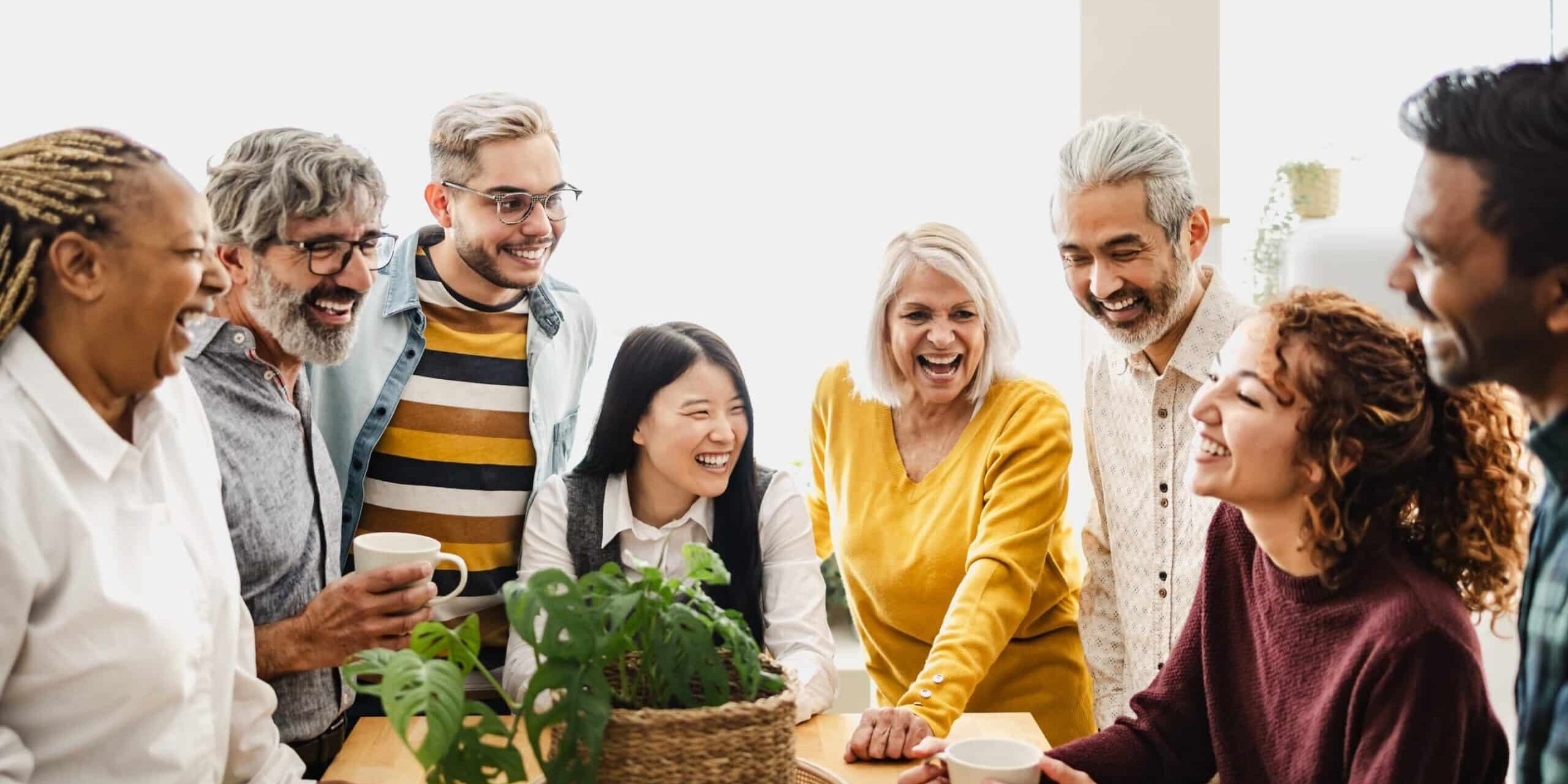 Group of diverse people smiling and talking around a table indoors.