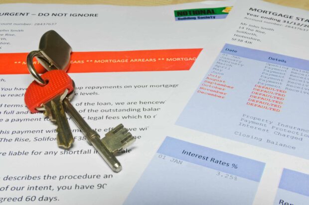 A mortgage arrears notice and mortgage statement with house keys on top.