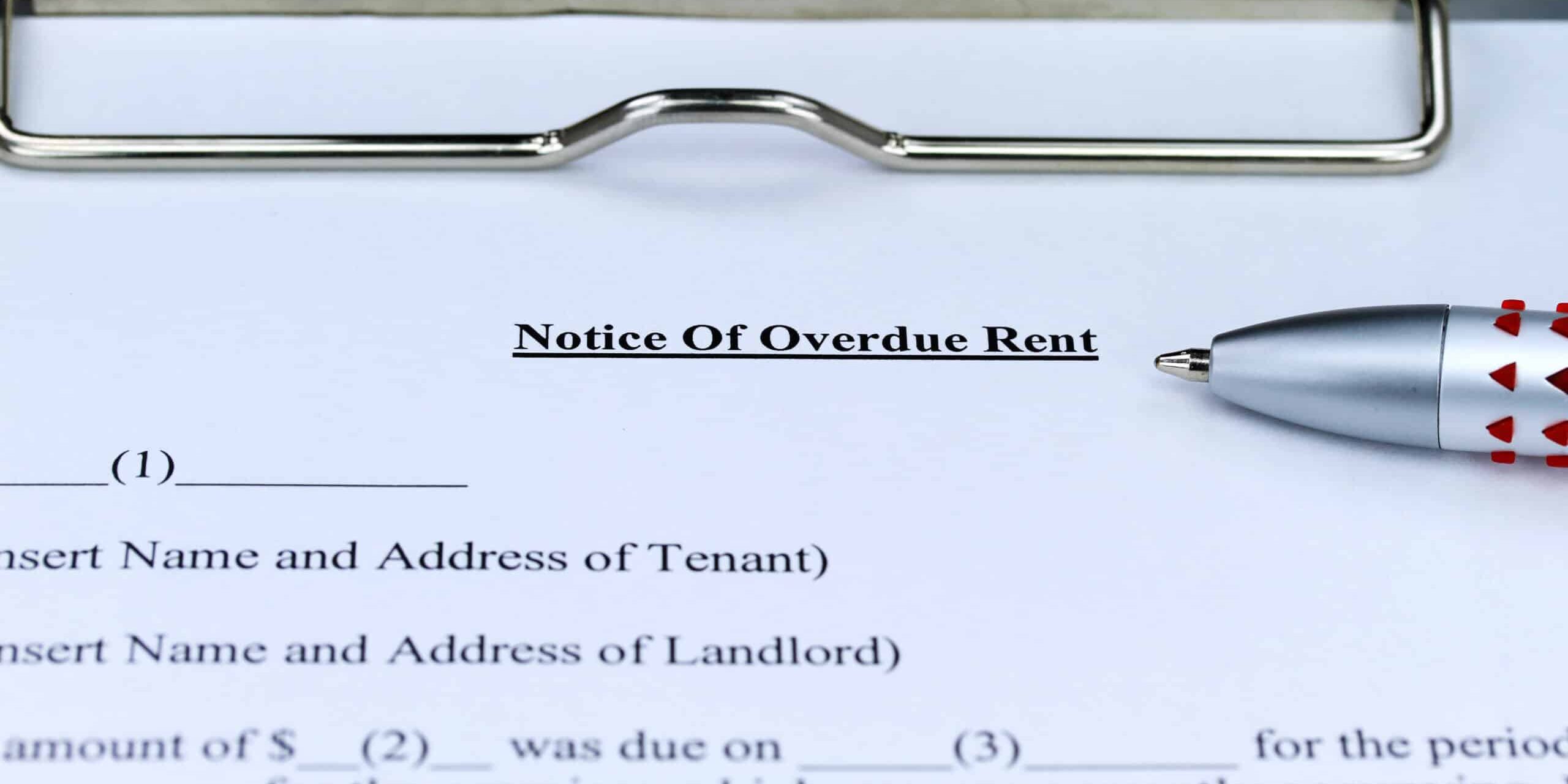 A close-up of a 'Notice of Overdue Rent' document on a clipboard with a pen placed next to it.