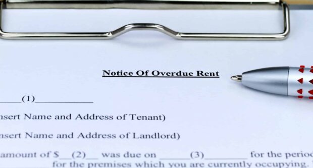 A close-up of a 'Notice of Overdue Rent' document on a clipboard with a pen placed next to it.