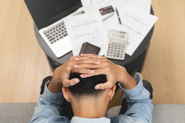 Man holding his head worrying about bills