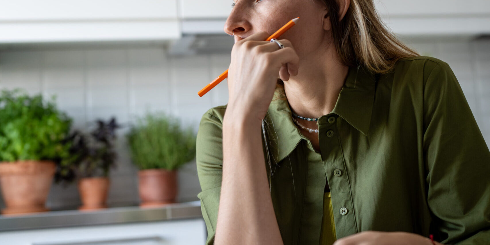 Thoughtful female analysing budget, verifying income and expenses, thinking while looking at window